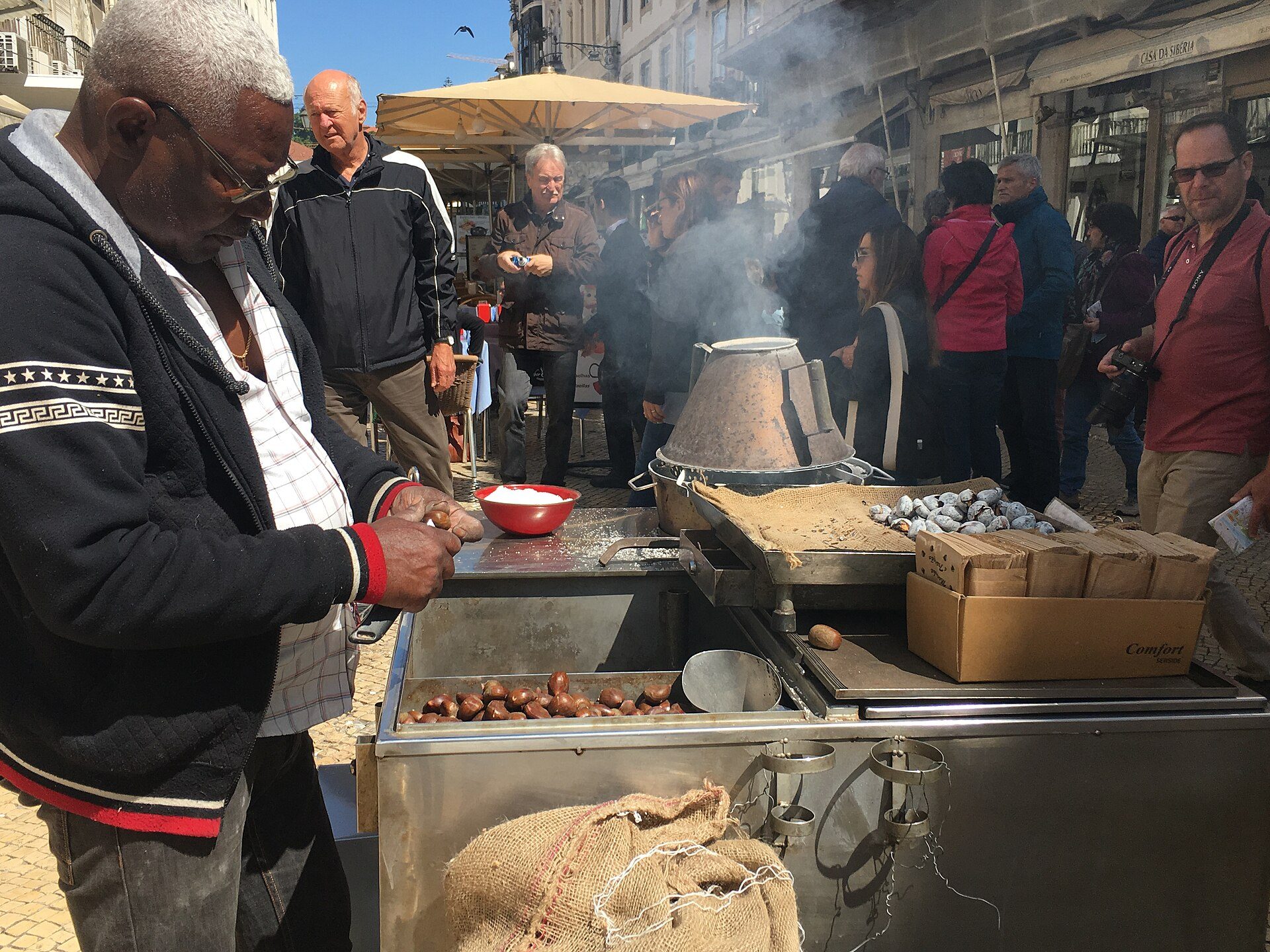 A street seller roasting chestnuts on a smoking cart in Lisbon